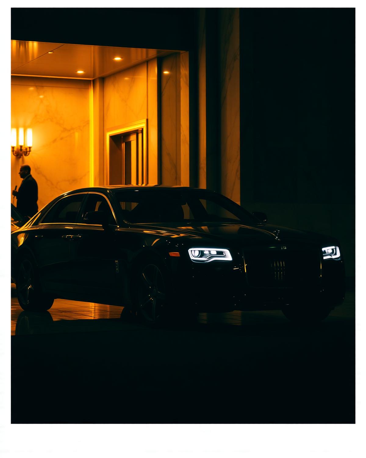 Black luxury chauffeured car at a marble hotel entrance